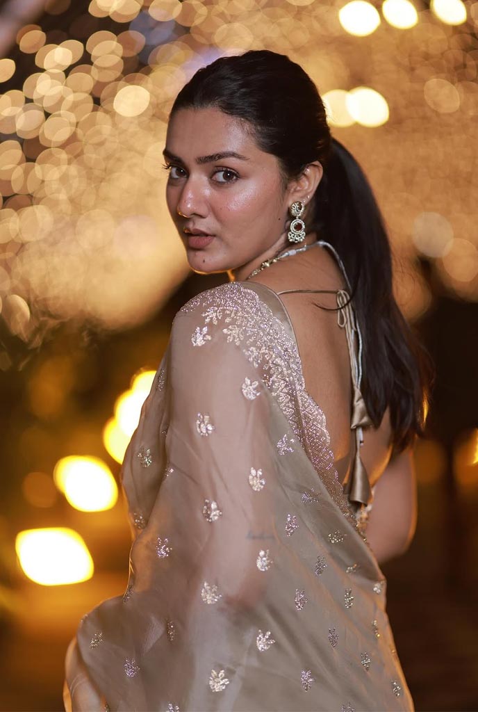 Laboni High-Profile Escort in elegant beige saree with shimmering embroidery posing gracefully against warm golden bokeh lights