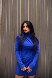 Aashini High-Profile Escort standing confidently in a fitted blue dress, highlighting refined beauty and elite escort service in Siliguri.