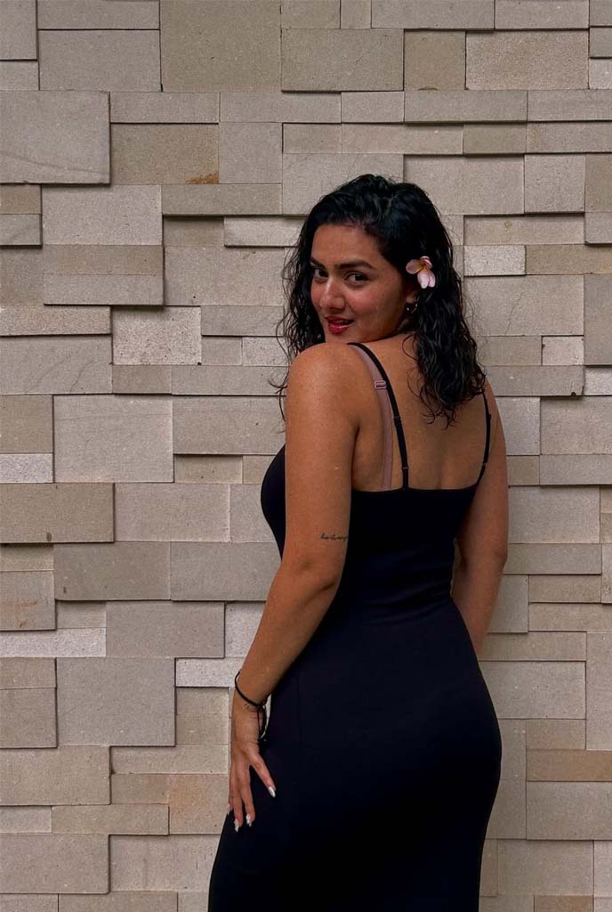 Laboni High-Profile Escort showcasing graceful side pose in fitted black outfit against textured wall