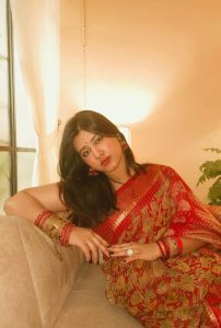 Oindrila Independent Escorts in elegant red saree posing indoors with graceful traditional look