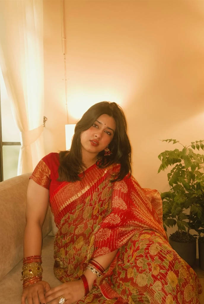 Oindrila Independent Escorts wearing red saree with premium jewelry in stylish indoor setting