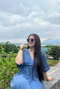 Esha Celebrity Escorts posing in elegant blue dress with scenic outdoor backdrop