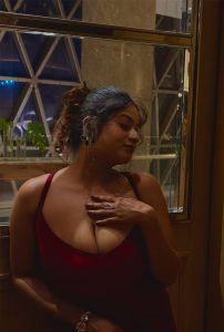 Nilisha Busty Escort posing gracefully indoors in a stylish red outfit with premium ambience