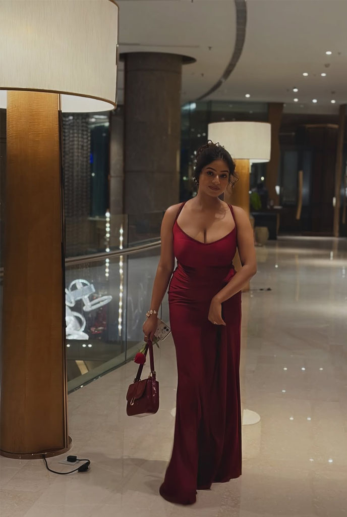 Nilisha Busty Escort walking confidently in an elegant red evening gown at a luxury hotel setting