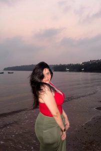 Sanchita Adhikari Hot Escorts posing on beach in red top and green skirt at sunset in Siliguri