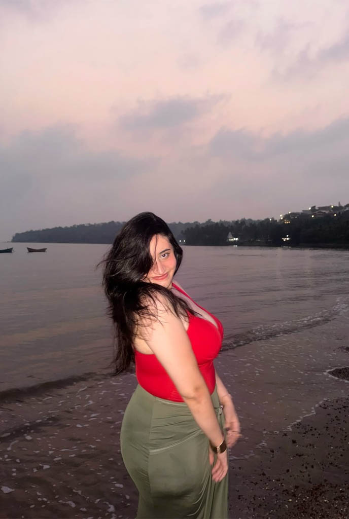 Sanchita Adhikari Hot Escorts posing on beach in red top and green skirt at sunset in Siliguri